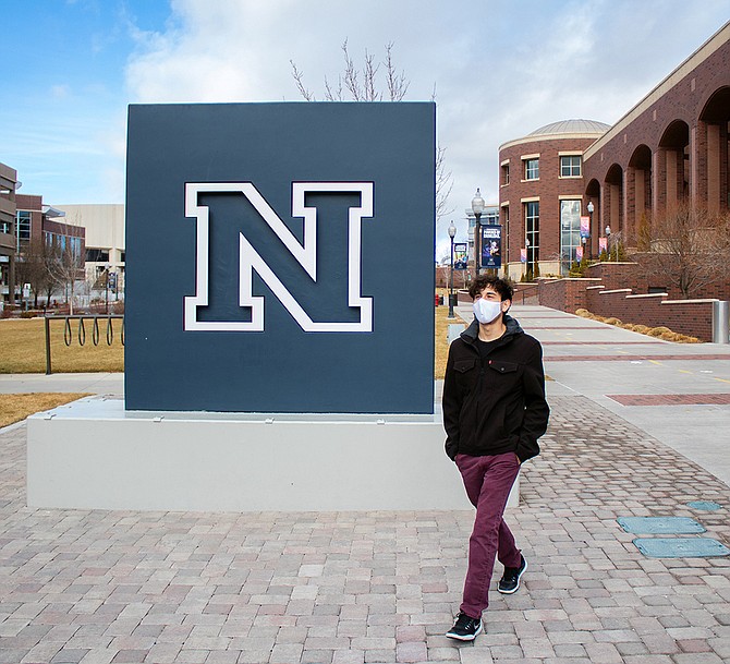 A students walks past the UNR logo.