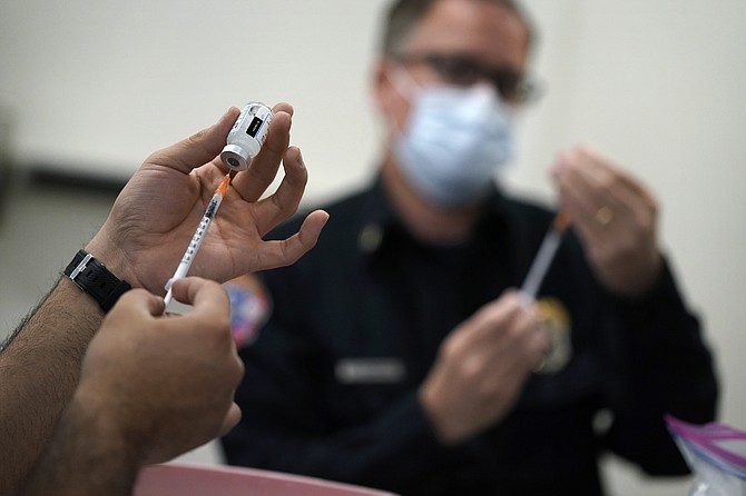 FILE - In this Feb. 10, 2021, file photo, people prepare doses of a COVID-19 vaccine at the Martin Luther King Senior Center, in North Las Vegas. (AP Photo/John Locher, File)