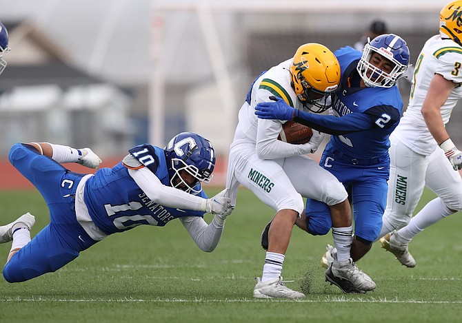 Carson High's Javier Arellano Barrios (2) and Salvador Mora-Rodriguez (10) tackle Bishop Manogue's Michael Schneider on Friday at Carson High.