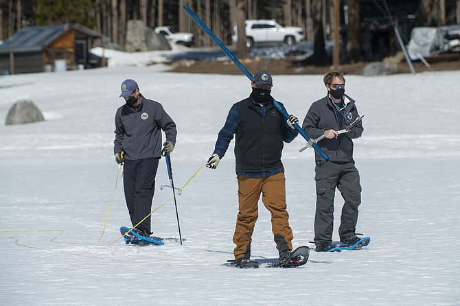 Aided by John Paasch, left, and Anthony Burdock, right, Sean de Guzman, chief of snow surveys for the California Department of Water Resources, prepares to check the depth of the snow pack during the fourth snow survey of the season at Phillips Station near Echo Summit, Calif., on Thursday. (AP Photo/Randall Benton)