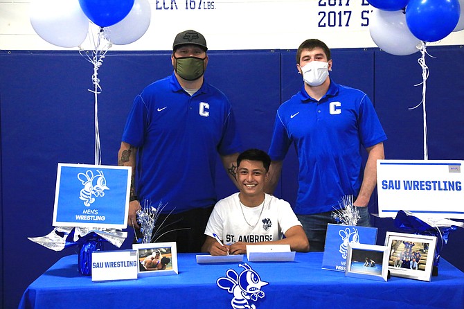 Ariel Vega of Carson High wrestling smiles after signing his National Letter of Intent on Friday to wrestle at St. Ambrose University in Davenport, Iowa next fall. Vega is pictured between head coach Nick Redwine, left, and assistant coach Nick Schlager.