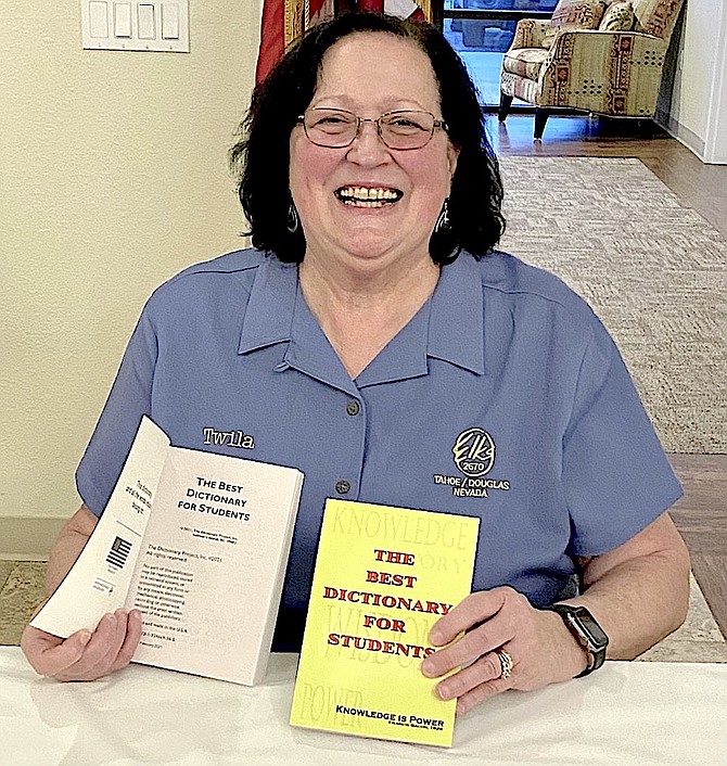 Elks Past Exalted Ruler Twila Otto holds two of the dictionaries the club is distributing around schools.