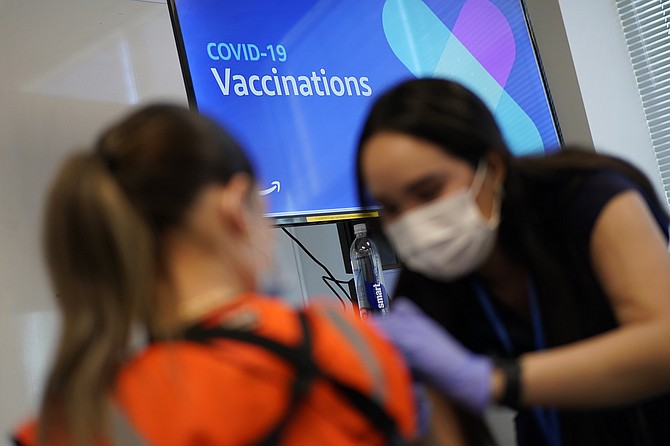 Registered nurse Sofia Mercado, right, administers a COVID-19 vaccine at a vaccination event for workers at an Amazon Fulfillment Center in North Las Vegas on March 31. (Photo: John Locher/AP, file)