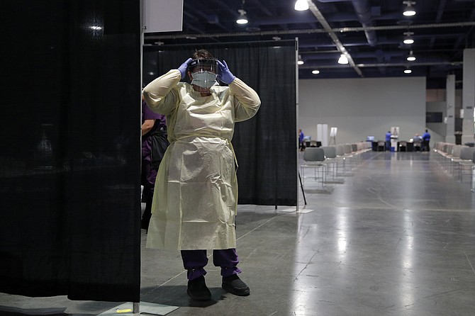 A nurse dons personal protective equipment before the opening of a temporary coronavirus testing facility for casino employees at the Las Vegas Convention Center last May. (Photo: John Locher/AP, file)