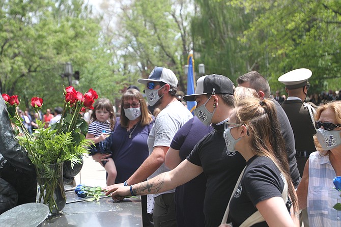 The family of NHP Sgt. Ben Jenkins places flowers at the peace officer's memorial on the legislative grounds Thursday. The 24th annual memorial to fallen officers drew officers from nearly every law enforcement agency in Nevada. (Geoff Dornan/Nevada Appeal)