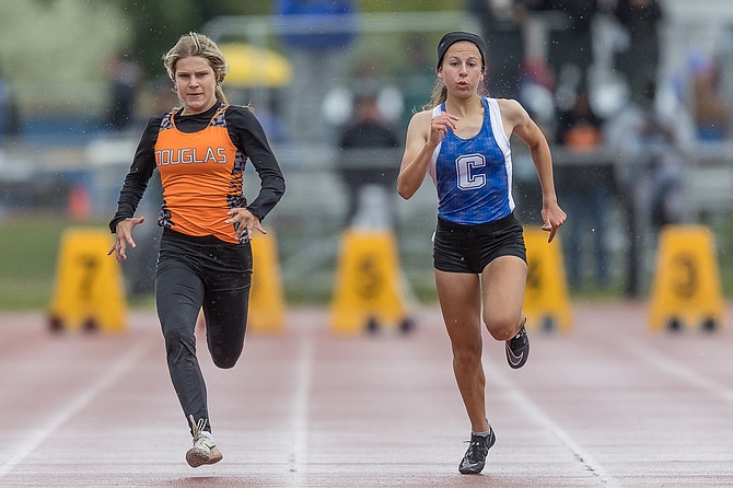 Carson High’s Natalyn Wakeling runs neck-and-neck with Douglas High’s Jessica James during the 100-meter dash Saturday. Wakeling bested James by three-hundredths of a second to win a regional championship.