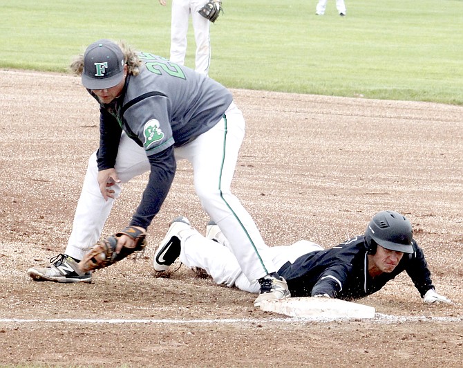 The Greenwave’s Damien Towne (23) keeps a Spring Creek player close to the first-base bag.