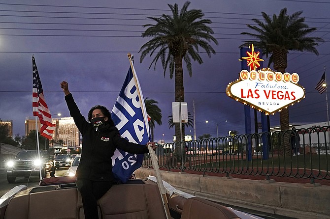 Socorro Ulloa, a supporter of then-President-elect Joe Biden and Vice President-elect Kamala Harris, carries flags while riding in the back of a limousine in Las Vegas on Nov. 7. (Photo: Jae C. Hong/AP, file)