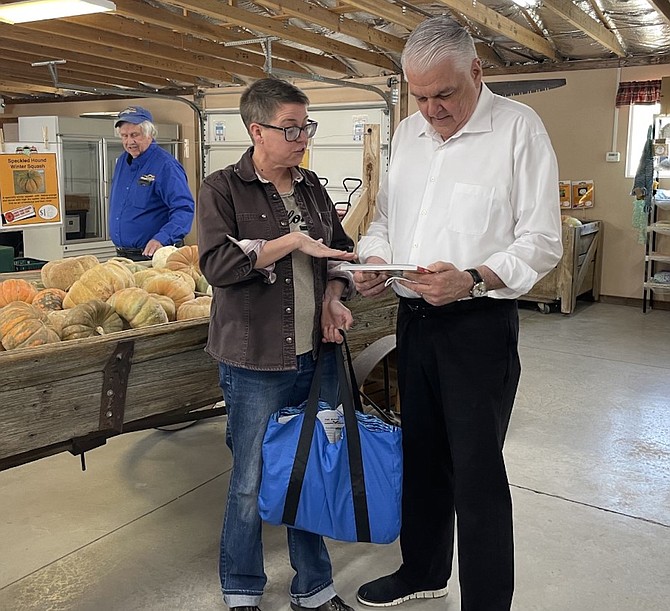 Kelli Kelly shares with Gov. Steve Sisolak information on food distribution. Rick Lattin, owner of Lattin Farms, is in the background.