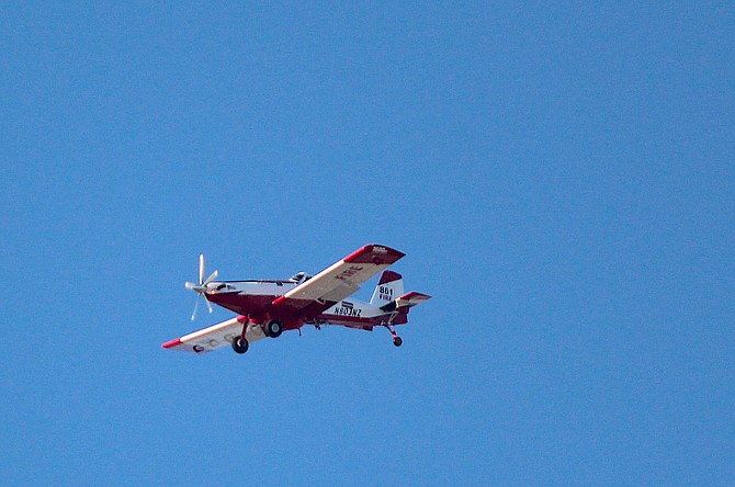 A firefighting aircraft flies over Indian Hills on Wednesday evening to battle the fire burning in Jacks Valley.
