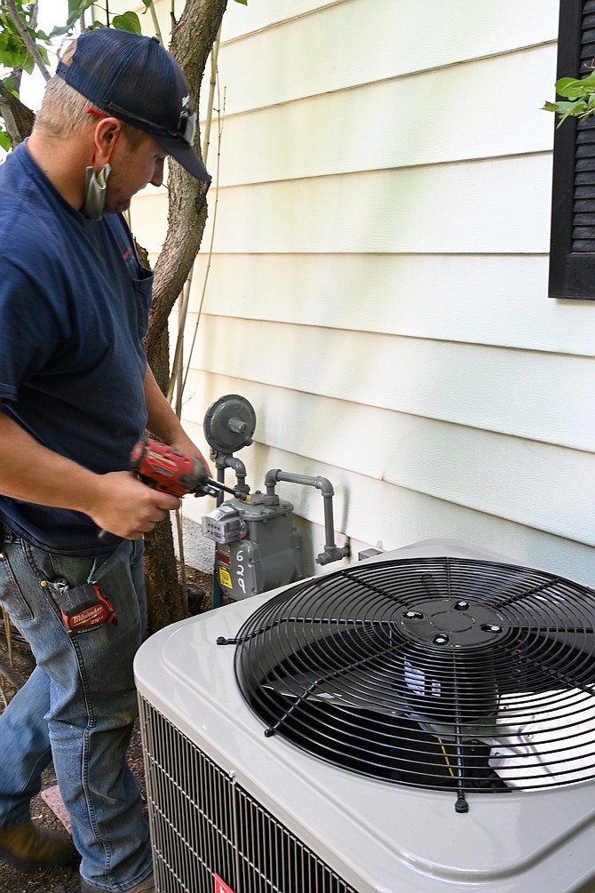 Trevor Edis, a technician at Roper’s Heating and Air Conditioning in Carson City, works on an AC unit on Wednesday, June 9.