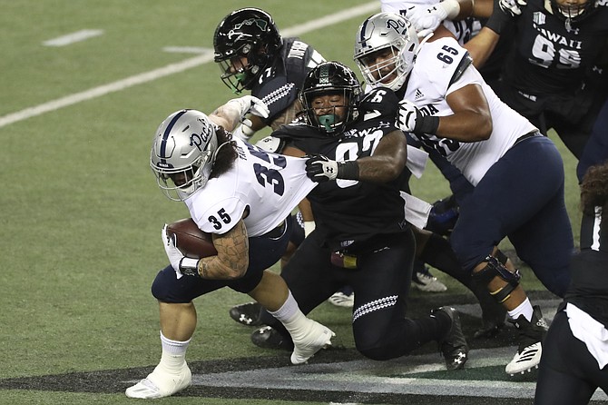 Nevada offensive lineman Aaron Frost (65) tries to keep Hawaii defensive lineman Zach Ritner (97) from pulling down Nevada running back Toa Taua (35) on Nov. 28 in Honolulu. (Photo: Marco Garcia/AP, file)