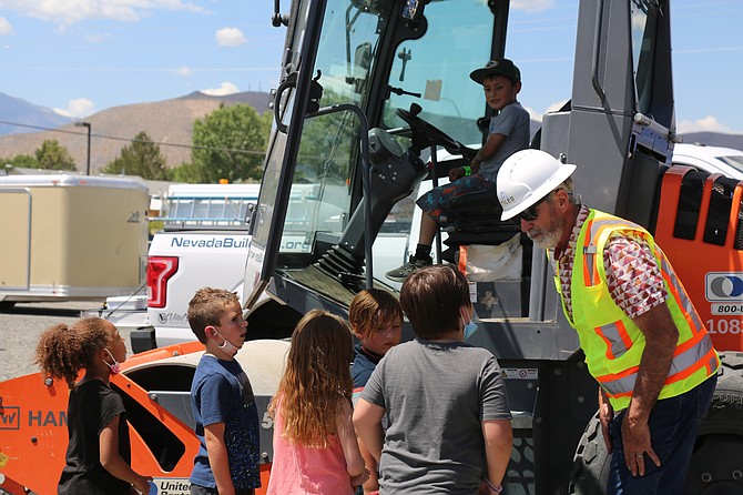 Showing off a cement roller, Bill Miles, founder and owner of Miles Construction, explains that construction workers need a key and proper training to drive equipment, in response to one child asking if they could “press the big red button” to start it.