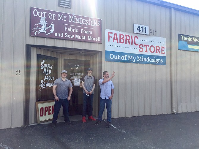 Posing next to their storefront, brothers Ian Densford and Ryan Lindsay smile for the camera, while Josh Densford breaks his pose to wave to a departing customer.