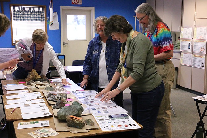 Beverly Vugteveen, forefront, who will begin the 2021-22 school year at Under the Magic Pine Tree, a preschool in Gardnerville this fall, examines various rocks and minerals Tuesday along with volunteer Patti McClelland, left, and with Karen Kimber, far left, of Flag View Intermediate School of Elko also participating, at the Nevada Mining Association’s 36th annual Northern Nevada Mineral Education workshop Tuesday in Carson City. (Photo: Jessica Garcia/Nevada Appeal)