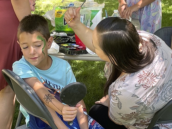 Tristan Bragg, 8, takes a look at the snake painted on his face by Kinderland’s new co-owner Nancy Rodriguez on Saturday at Bowers Mansion. Rodriguez and Caitlin Castaneda, not pictured, are assuming ownership of Kinderland. (Photo: Jessica Garcia/Nevada Appeal)