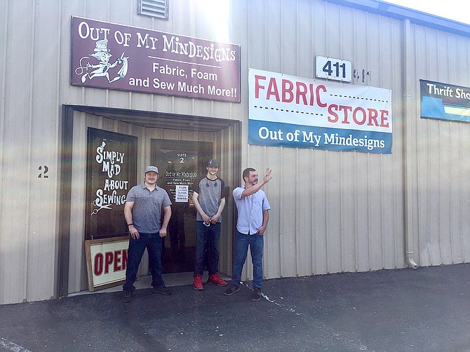 Posing next to their storefront, brothers Ian Densford and Ryan Lindsay smile for the camera, while Josh Densford breaks his pose to wave to a departing customer.