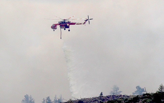 A firefighting helicopter drops water on the East Fork Fire burning in Alpine County.