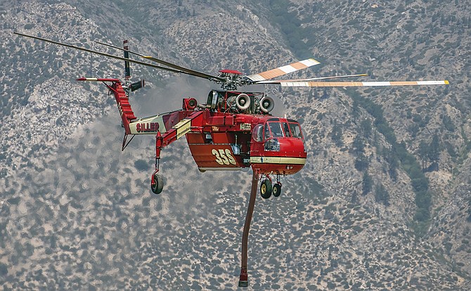A firefighting helicopter flies in Alpine County to help hand crews put out the East Fork Fire. JT Humphrey Photo