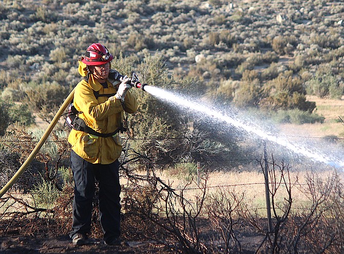 A wildland firefighter douses a hot spot at the Jacks Valley Fire on Friday evening.