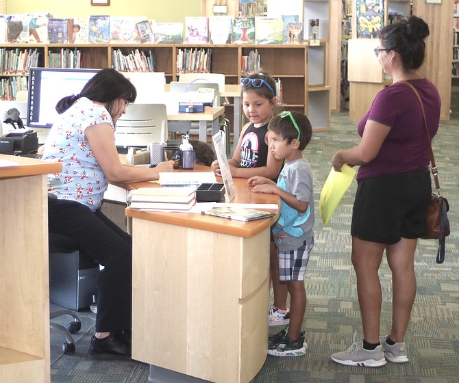 Maria Gill, left, assists patrons last week at the Churchill County Library. The library foundation is hosting an open house on Thursday from 6-8 p.m.