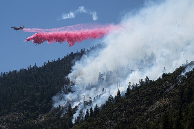 An air tanker drops fire retardant to battle the Dixie Fire in the Feather River Canyon in Plumas County, Calif., on Wednesday. Residents were warned to be ready to evacuate as a growing wildfire bears down on two remote Northern California communities near a town largely destroyed by a deadly blaze three years ago. The fire that broke out Tuesday afternoon has chewed through more than 1.8 square miles of brush and timber near the Feather River Canyon area of Butte County. (Photo: Paul Kitagaki Jr./The Sacramento Bee via AP)
