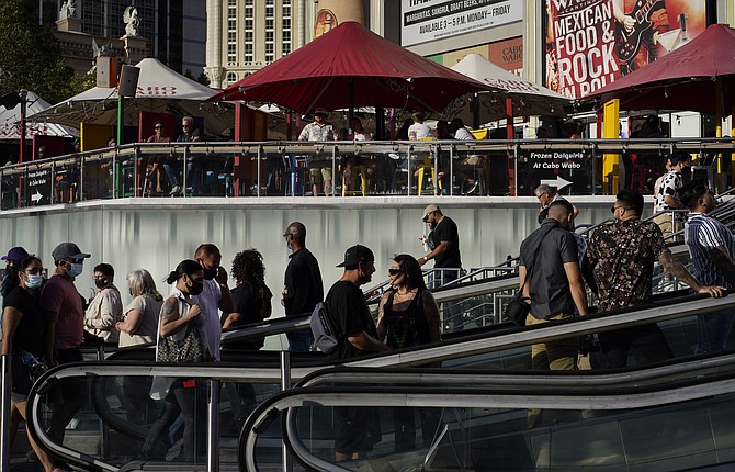 In this April 24, 2021, file photo, people walk as others dine on the Las Vegas Strip. (AP Photo/John Locher, File)