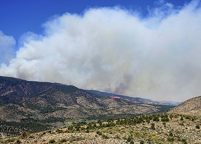 A pink stripe of retardant is dropped from a fire tanker at around 12:30 p.m. Wednesday in this photo by Topaz Ranch Estates resident John Flaherty. Smoke from the fire has increased, but aircraft are still able to fly.