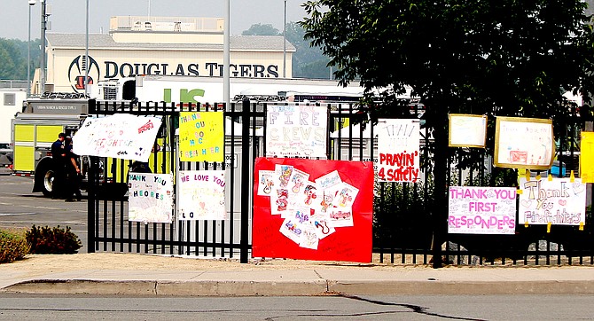 Signs thanking firefighters on Saturday and urging them to stay safe line the fence at Douglas High School where they are staged for the Tamarack Fire.