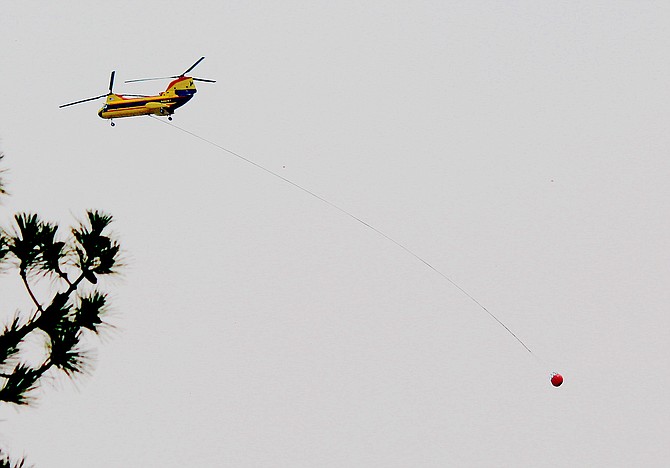 A helicopter tows a water bucket over Minden on Monday.