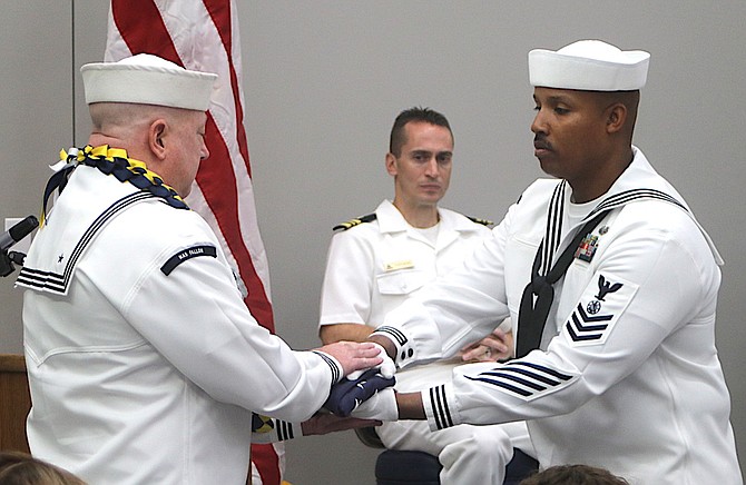 Mass Communications Specialist 1 Larry Carlson, left, receives the U.S. flag during his retirement ceremony.