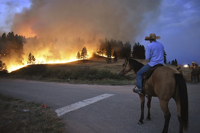 Rowdy Alexander watches from atop his horse as a hillside burns on the Northern Cheyenne Indian Reservation on Wednesday, Aug 11, 2021, near Lame Deer, Mont. The Richard Spring fire was threatening hundreds of homes as it burned across the reservation. (AP Photo/Matthew Brown)