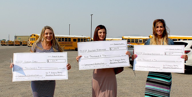 Betts Foundation award recipients Sarah Caro, Allison Kirwood and Montana Hammond hold representations of their $1,000 checks awarded at Tuesday’s Douglas County School Board meeting.