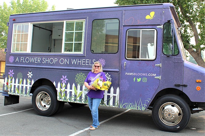 Pam Karg, owner of Pam’s Blooms, stands beside “Petunia,” her Flower Shop on Wheels.
