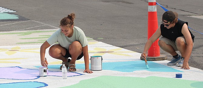 Seniors Sativa Cark, left, and Cody Shelton enjoy their final days before school starts on Monday. Both students are painting their individualized parking spots at the high school.