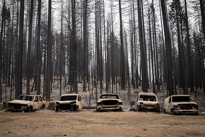 Scorched cars rest on a property on Winding Way, Wednesday, Aug. 18, 2021, in Grizzly Flats, Calif., after the Caldor Fire burned through the area. (AP Photo/Ethan Swope)