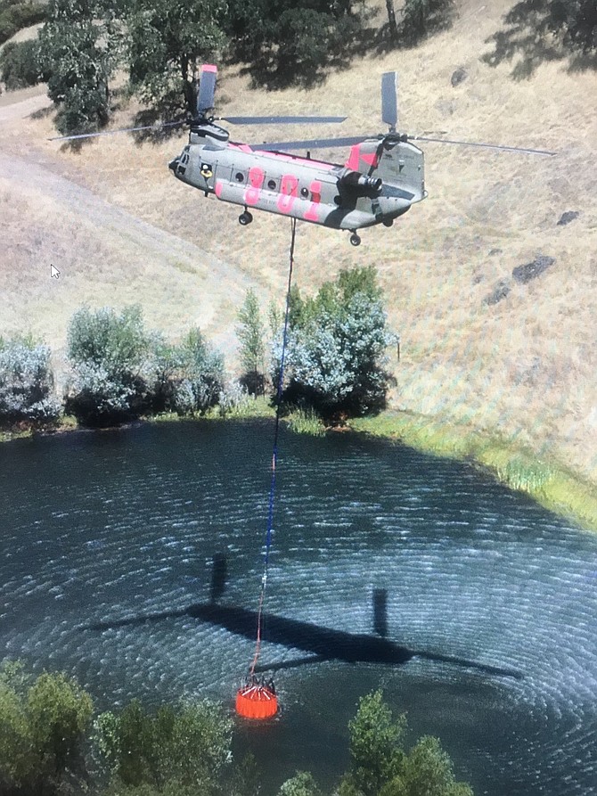A Nevada National Guard helicopter dips water to drop on the Caldor Fire burning south of Pollock Pines.