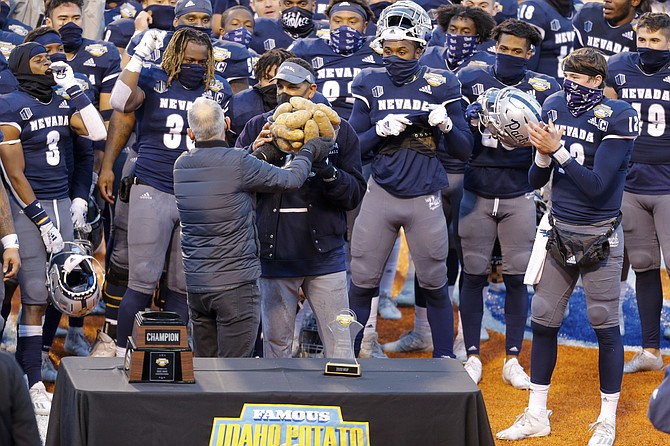Nevada coach Jay Norvell accepts the trophy from Kevin McDonald, executive director of the Famous Idaho Potato Bowl, after the Pack’s 38-27 win against Tulane on Dec. 22, 2020, in Boise, Idaho. (AP Photo/Steve Conner)