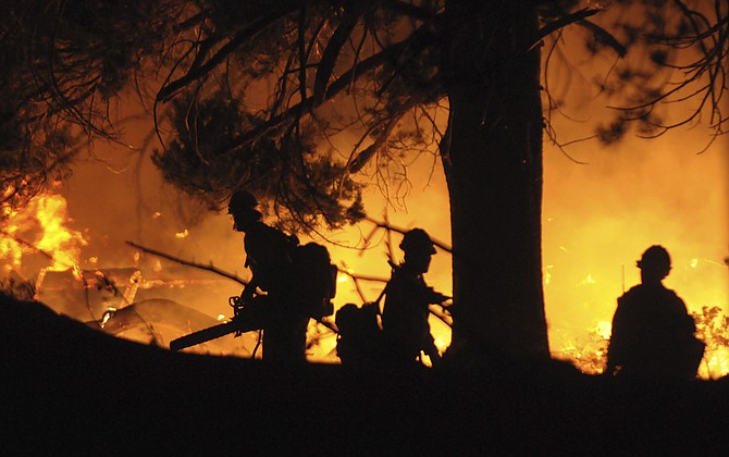A trio of Tahoe National Forest firefighters use chainsaws to cut a fire line around surrounding homes in the Christmas Valley area to protect them from the Caldor Fire on Monday, Aug. 30, 2021, near South Lake Tahoe, Calif. (Photo: Elias Funez/The Union via AP)