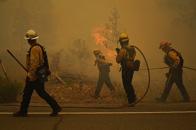 Firefighters carry water hoses while battling the Caldor Fire near South Lake Tahoe, Calif., Tuesday, Aug. 31, 2021. (AP Photo/Jae C. Hong)