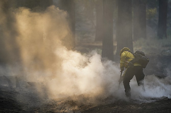 A firefighter mops up hot spots from the Caldor Fire near South Lake Tahoe, Calif., on Wednesday, Sept. 1, 2021. (AP Photo/Jae C. Hong)