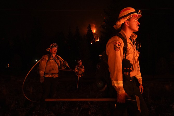 Firefighters are lit by a backfire set to prevent the Caldor Fire from spreading near South Lake Tahoe, Calif., on Sept. 1, 2021. (AP Photo/Jae C. Hong, File)