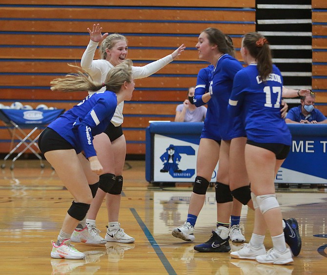 The Carson High volleyball team celebrates after winning match point against Reed at home Wednesday night.