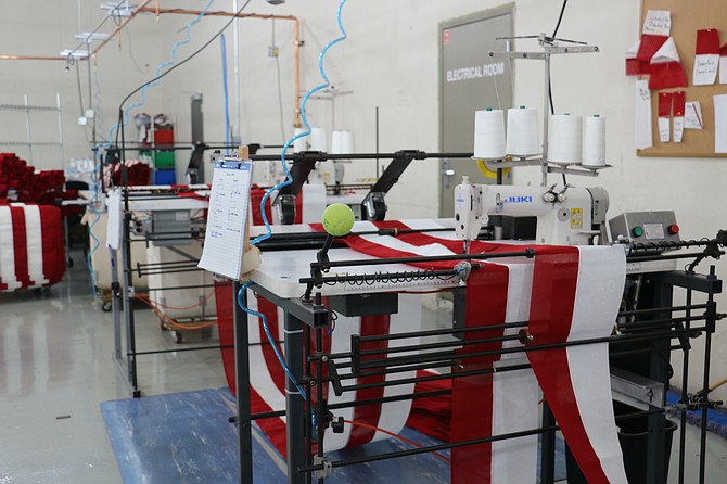 The striping machine at North Bay Industries stitches together long rows of red and white fabric, accounting for seven short stripes that sit beside the stars and the six long stripes lining the bottom of the American flag. (Photo: Faith Evans/Nevada Appeal)