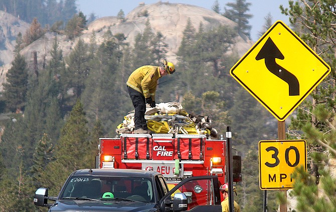 Firefighters roll up hose on Highway 88 in Alpine County on Sept. 16 before the highway opened Sept. 21.