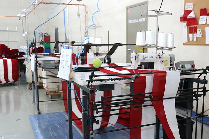 The striping machine at North Bay Industries' Carson City manufacturing site at 715 Industrial Park Drive stitches together long rows of red and white fabric, accounting for seven short stripes that sit beside the stars and the six long stripes lining the bottom of the American flag.