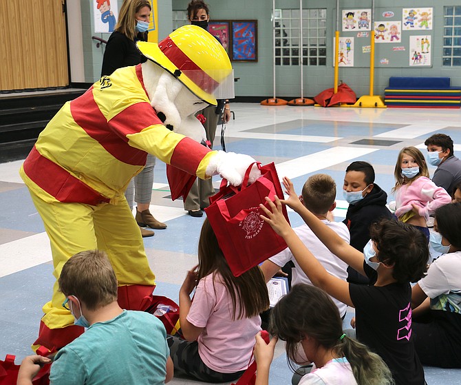 Sparky the Dog provides gift bags to Fremont Elementary School students on Wednesday in a presentation announcing the winners of the “2021 State of Nevada Fire Prevention Week Poster Contest.” (Photo: Jessica Garcia/Nevada Appeal)