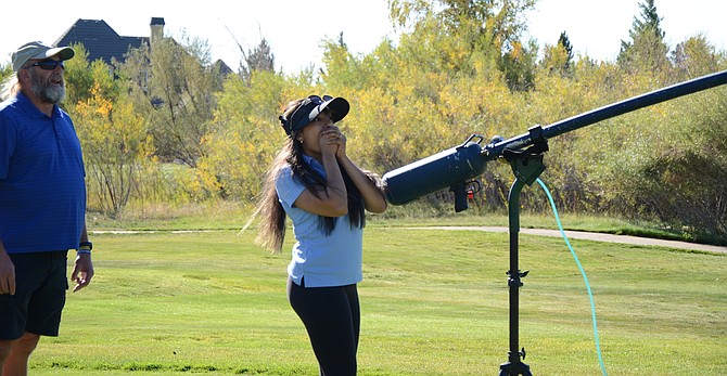 The power and distance of a ball launcher fascinated WNC student volunteer Dulce Ruiz at the Golf for Education tournament.