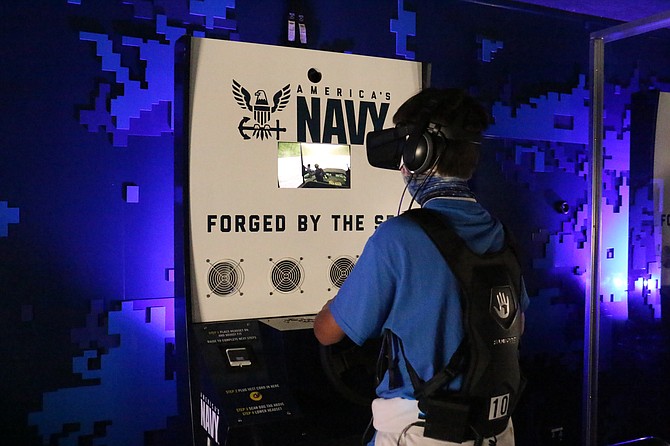 Carson High School freshman Adan Pazos tries his hand on the Navy’s Nimitz mobile virtual reality tech, which included an Oculus headset and a wearable SubPac to simulate the sensation of rescuing Navy SEALs in a mission. (Photo: Jessica Garcia/Nevada Appeal)
