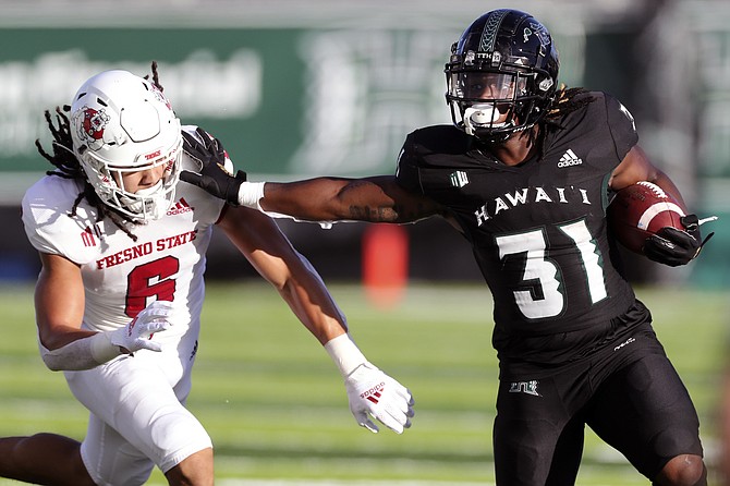 Hawaii running back Dedrick Parson stiff-arms Fresno State linebacker Levelle Bailey during their game Oct. 2, 2021, in Honolulu. (AP Photo/Marco Garcia)